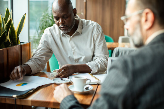 Two men reviewing a chart over coffee in a cafe