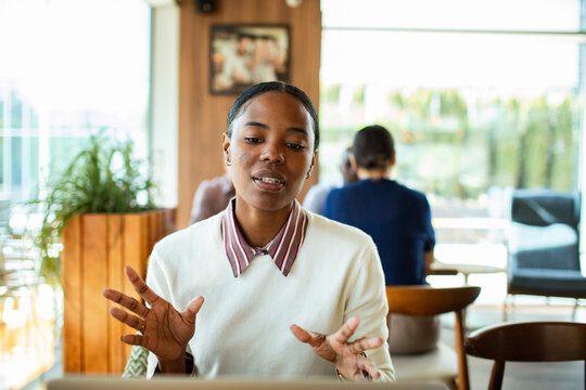 Woman explaining on a video call in a cafe