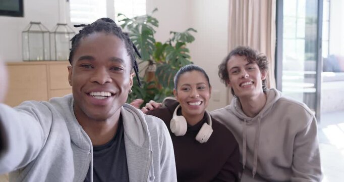 Diverse friends sitting on couch, left friend reaching for camera, recording and saying goodbye
