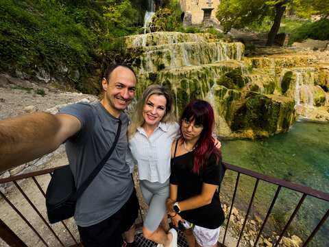Three people taking a selfie posing for a, in natural waterfall and stone steps, with waterfall, stone steps, railing, with stone, metal railing, water texture.