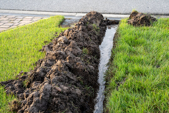 Water filling a ditch being dug in a yard to install a downspout drain to prevent flooding