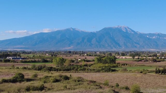 Aerial view of the majestic Mount Olympus rising above the fields and coastal landscape of Paralia Katerinis, Pieria, Greece.