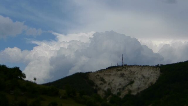 Miniature tilt shift effect timelapse of storm cumulus clouds moving fast over a weather station on top of a hill focus on dramatic dark cloudscape meteorology science concept background
