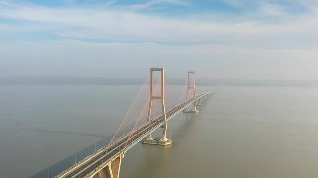 Aerial view of Suramadu Bridge spanning the Madura Strait under a hazy sky in Kecamatan Labang, Jawa Timur, Indonesia.