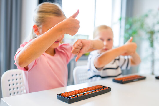 Close-up of children using abacus gestures and abacus to practice mental arithmetic, counting and calculation skills during a classroom lesson.