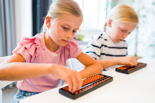 Children using abacuses to practice mental arithmetic, counting and calculation skills during a classroom lesson.