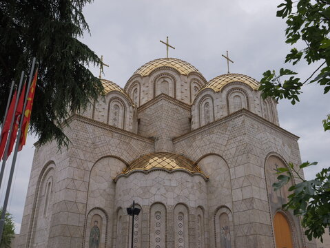 View of the Church of Saints Constantine and Helena with its distinctive golden domes and stone facade under a cloudy sky in Shkupi, Qyteti i Shkupit, North Macedonia.