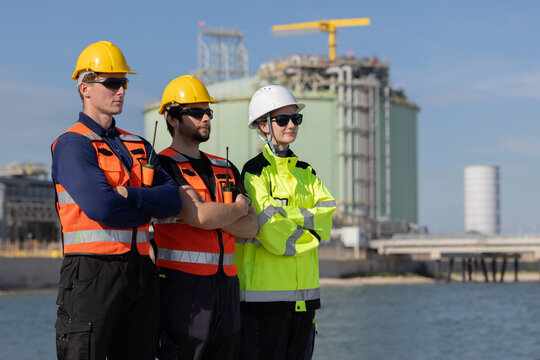 Engineers with cross arm pose at oil refinery site