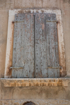 View of a weathered wooden window shutter on a rustic stone wall in the historic old town of Rovinj, Istria County, Croatia.