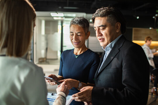 Two business attendees check in at event registration desk