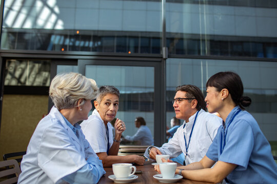 Medical team chatting over coffee on hospital terrace