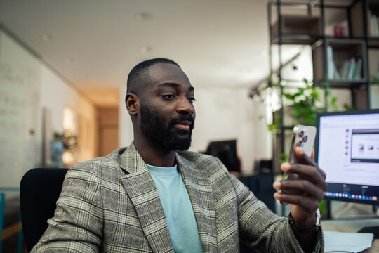 Man checking smartphone at desk in office