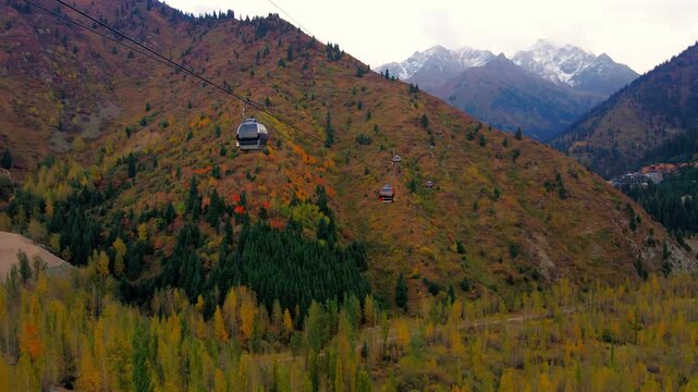 Cinematic autumn landscape of Almaty, Kazakhstan, featuring colorful mountain scenery, snowy Tien Shan peaks, Shymbulak ski resort, Medeu and the cable car.