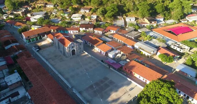 Aerial view of the historic church and plaza in the coastal village of Cepe, surrounded by lush green hills and traditional houses in Maracay, Aragua, Venezuela.