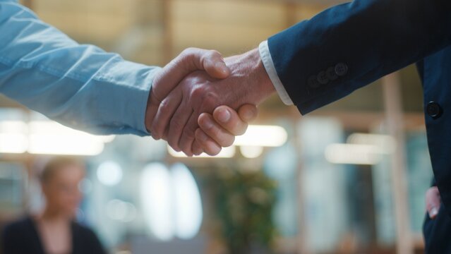 Cropped view two unrecognizable Caucasian business men shaking hands in office. Businessmen handshake close up unknown males agents greeting in company coworkers handshaking cooperating work in agency