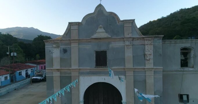 Aerial view of the historic church in the coastal village of Cepe with surrounding colorful houses and mountain backdrop in Maracay, Aragua, Venezuela.