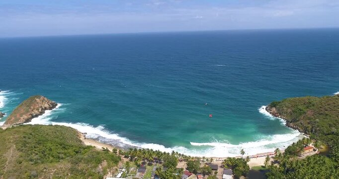 Aerial view of Cepe beach with turquoise waters, sandy shores, and lush green hills in Maracay, Aragua, Venezuela.
