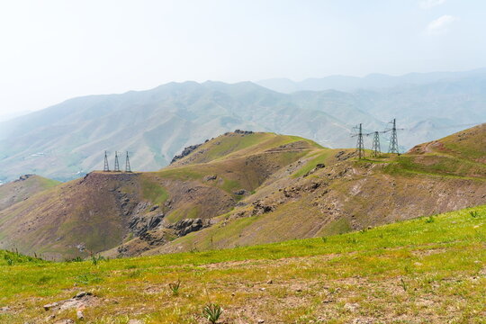Power lines crossing mountains near Angren in late Spring in hazy weather