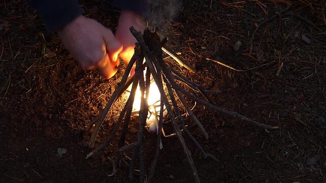 Close up of striking a magnesium fire starter to ignite a small campfire at night
