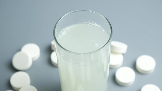 Effervescent pill dissolving in glass with scattered tablets around