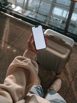 Traveler hand smartphone blank screen airport luggage suitcase travel journey terminal vacation waiting departure mobile