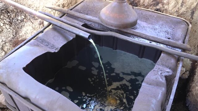Traditional crude oil distillation process into diesel and kerosene using rustic manual equipment at Teksas Wonocolo petroleum field in Bojonegoro, East Java, Indonesia, showcasing local industry.