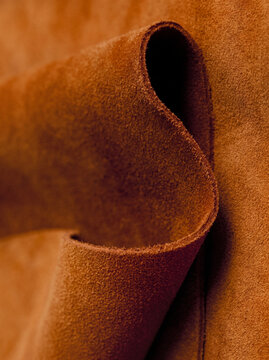 Close-up of rolled brown suede leather with soft texture and folds, luxury material detail
