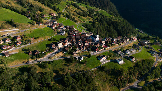 Aerial drone landscape of Ergisch alpine village in Switzerland, featuring the iconic church steeple, traditional roofs, and scenic green mountain valley in the Alps, Ergisch, Wasserfall Turtmann
