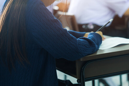 Female Student Wearing Blue Sweater Writing Final Exam in Classroom