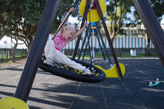 Carefree Little Girl Balancing and Playing on Web Nest Swing at Outdoor Playground