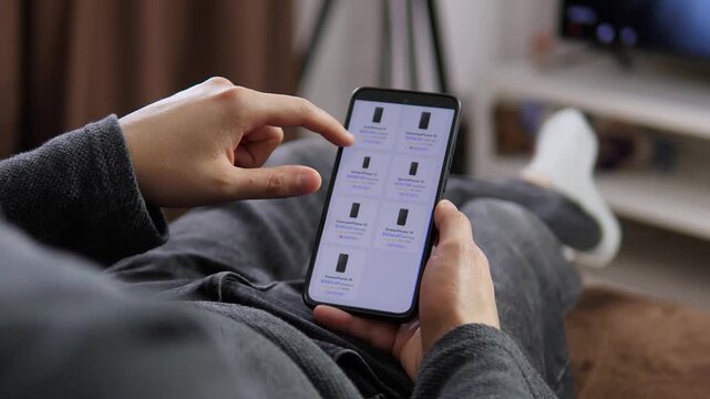 Person browses a mobile phone catalog on a smartphone, comparing prices, ratings and models as digital retail reshapes how consumers research and buy electronics.