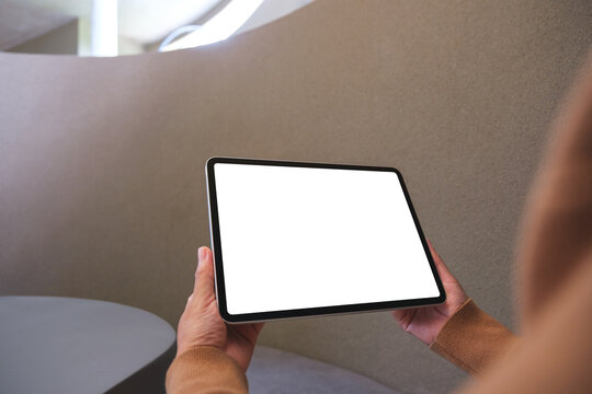 Mockup image of a woman holding digital tablet with blank white desktop screen in cafe