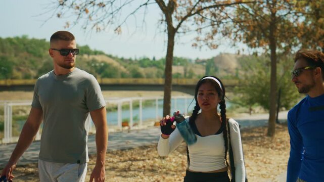 Three friends walk and converse in a park, enjoying a sunny day outdoors. They share a moment of active fitness and friendship, embodying a healthy lifestyle.