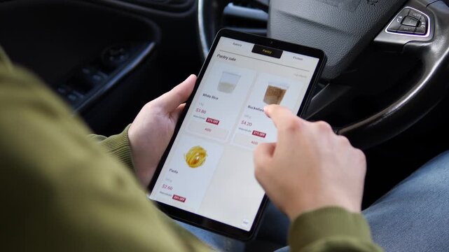 Person browses discounted groceries on a tablet, switching sale categories and comparing pantry staples as digital food shopping focuses on savings and price-conscious buying.