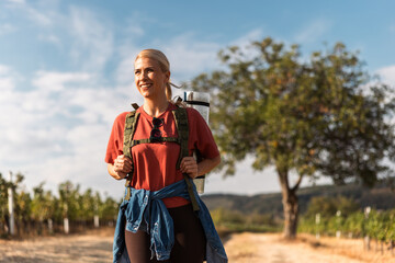 Obraz premium Hiking gear and vibrant landscape with smiling woman on sunny trail