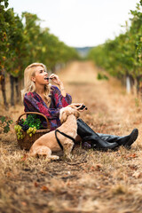 Obraz premium Woman enjoying grapes with dog in vineyard during harvest season