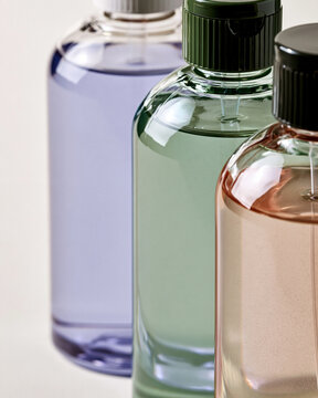 Assorted beauty products with pastel colored liquids in clear bottles, representing a range of cosmetic items for skincare and wellness routines in a spa environment