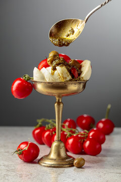 Mozzarella with pesto sauce, green olives, and red cherry tomatoes.