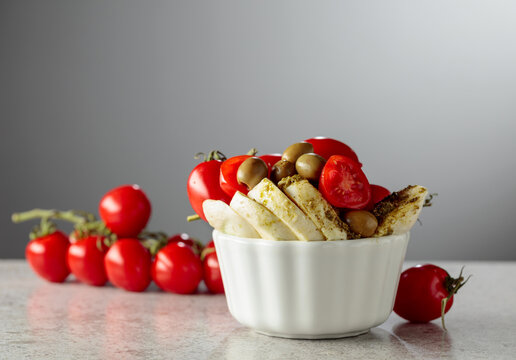Mozzarella with pesto sauce, green olives, and red cherry tomatoes.