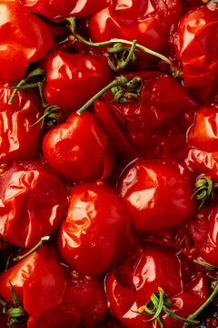 Roasted red cherry tomatoes on a black background.