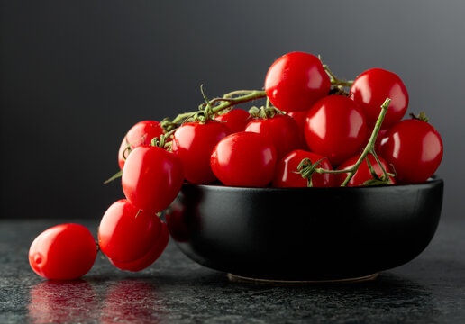 Small red cherry tomatoes on a black background.