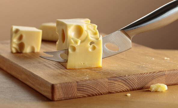 Cheese and knife on a wooden cutting board.