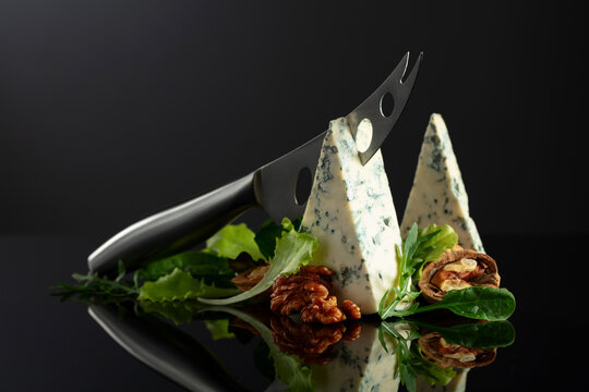 Blue cheese with knife, walnuts and fresh greens.