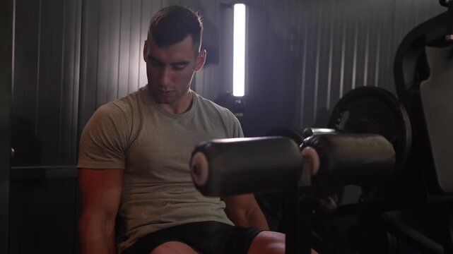 Muscular athlete training legs on leg extension machine