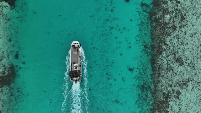 青い海に白い航跡を描きながら進む漁船の俯瞰空撮映像