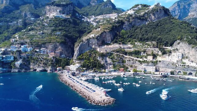 Aerial lateral flyby along Amalfi harbor piers and cliffside coastline 4K