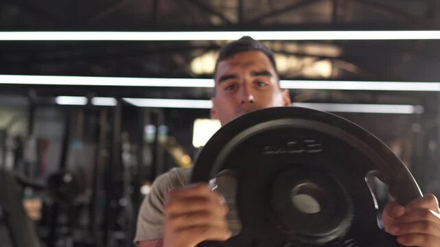 Determined athlete training with weight plate at gym