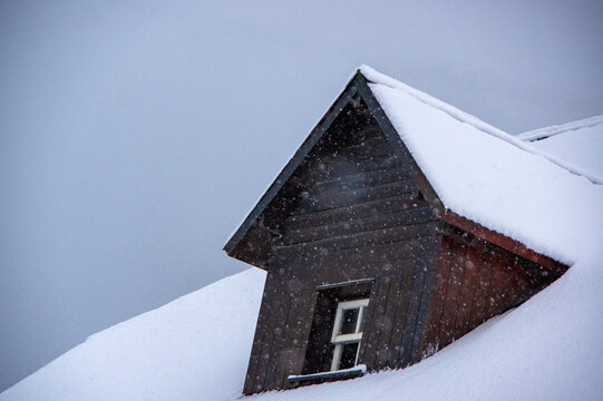 Wooden dormer window under snow on a snowy day
