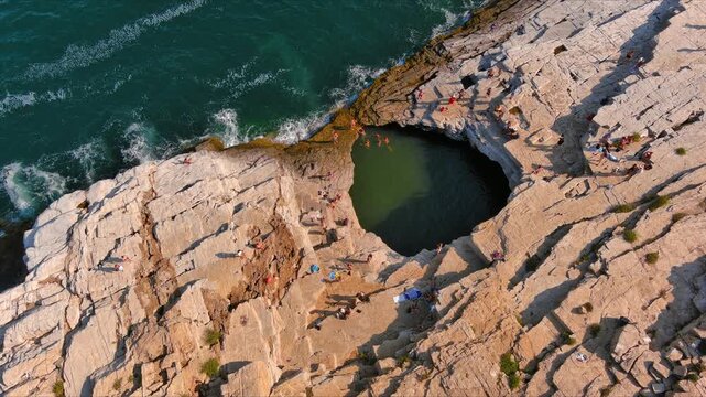 Aerial view of the Giola natural pool surrounded by rugged limestone cliffs and the Aegean Sea in Thasos, Greece.