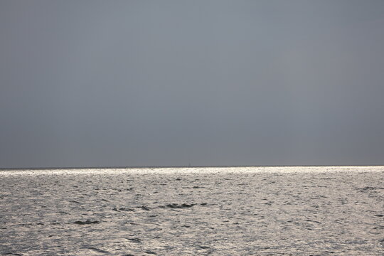 Evening sun casting a warm glow through the clouds over a calm bay.